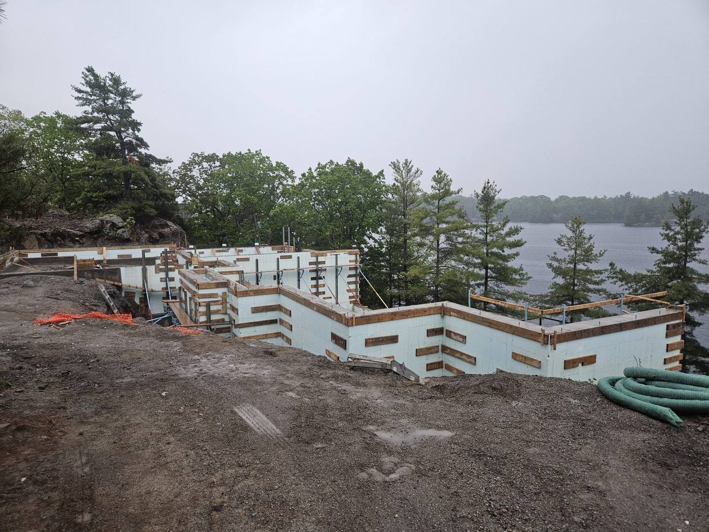 Stepped ICF foundation following a sloped, rocky lot, ready for drainage and backfill