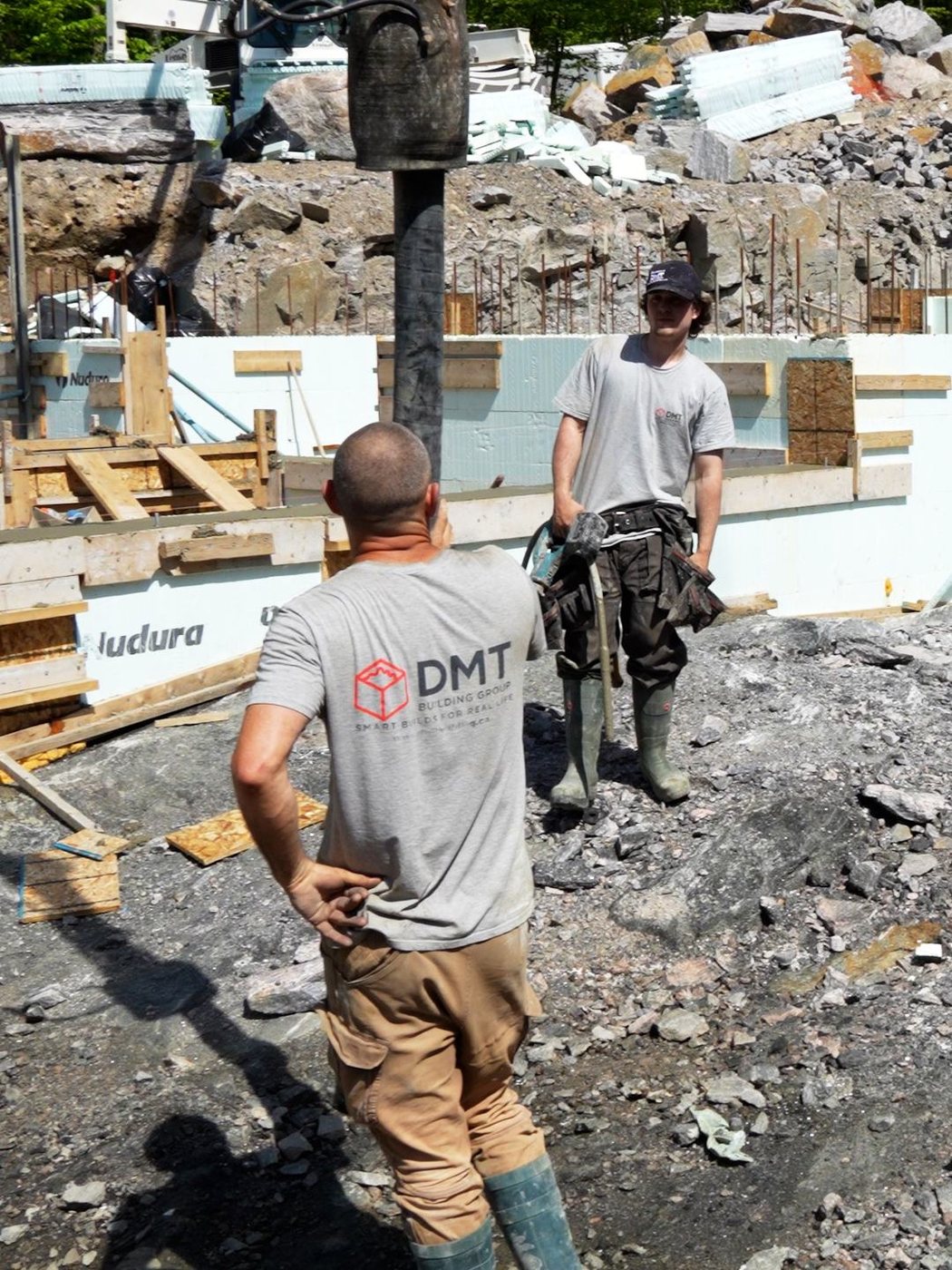 Two DMT crew members in front of a braced Nudura ICF wall, its printed foam face part of the answer to how long do ICF homes last