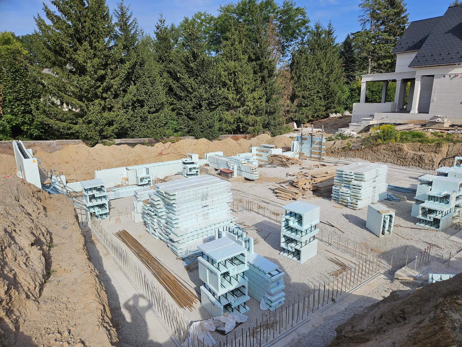 ICF blocks staged on a poured footing with rebar dowels in place, ready to set